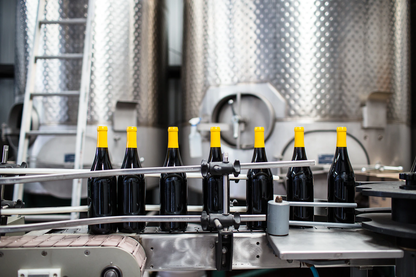 Línea industrial de embotellado con botellas y equipo de acero inoxidable.